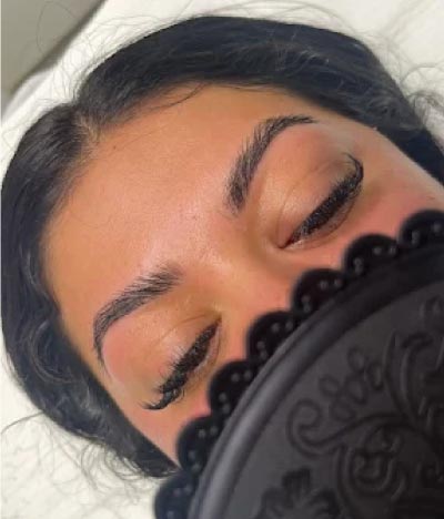 Close-up of a client’s professionally applied eyelash extensions and manicured eyebrows, showcasing the detailed skincare and esthetician techniques focused on complexion and beauty.